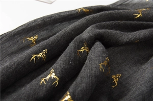 Detail of dark grey scarf fabric with golden reindeer print and soft cotton texture