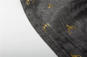 Detail of grey winter scarf showing gold reindeer print and premium double-stitch hem