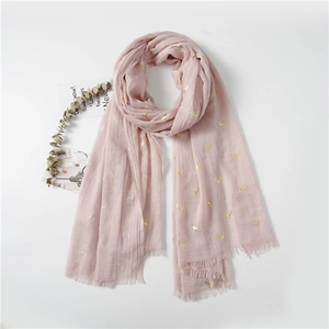 Detail of dusty pink scarf with golden reindeer patterns and fine fringe edges