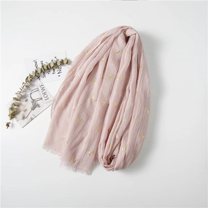 Detail of pink cotton scarf with golden reindeer print and delicate fringe edges