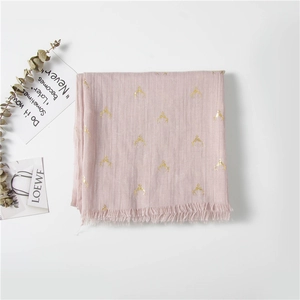Macro detail of pink scarf showing golden deer horn patterns and fringe trim edges