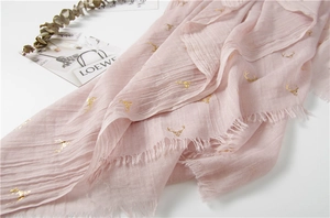 Detail view of pink cotton linen scarf with gold foil reindeer print and tassel edges