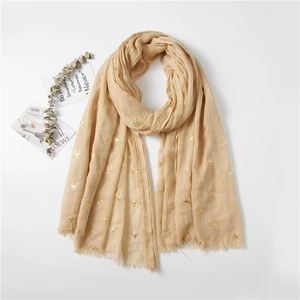 Detail of beige scarf featuring golden reindeer print and delicate fringed edges