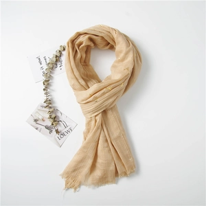 Detail of warm beige scarf with gold deer print, linen texture, and frayed edges style
