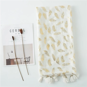 White linen scarf with golden feather prints and tassels on minimalist background