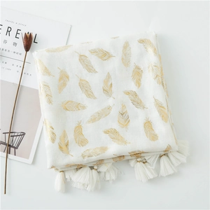 Detail of white pashmina shawl featuring golden feather prints and handmade tassels