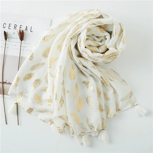 White scarf with gold feather print and white tassels on minimalist white background