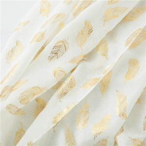 Detail of white cotton scarf with elegant gold foil feather patterns and airy texture