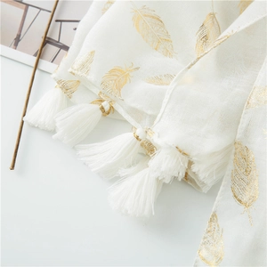 Close-up of white voile scarf with gold feather prints and soft fringe texture
