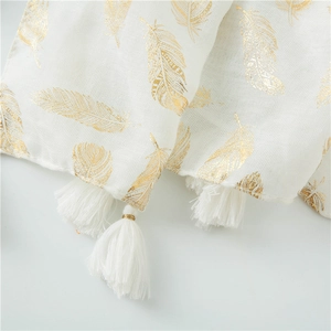 Macro detail of white scarf with gold feather foil print and soft tassel trim