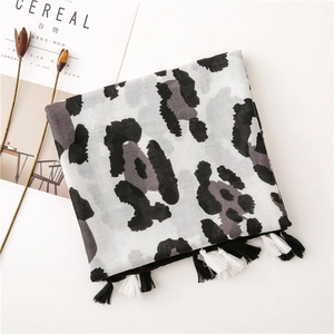 Detail of leopard print scarf with black and white tassels on a minimalist background