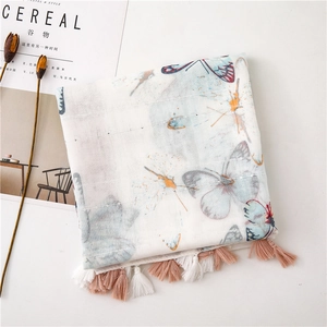 Close-up of white cotton linen scarf with butterfly prints, sequins and fringe details