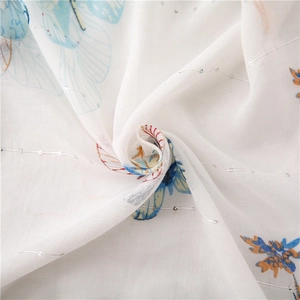 Close-up of white cotton linen fabric with butterfly print and silver sequins details