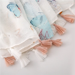 Detail of a lightweight butterfly print scarf featuring soft mesh texture and colorful tassels