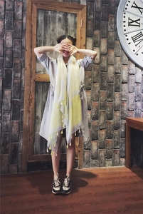 Light yellow geometric pattern scarf with fringe tassels shown on a model in a retro room