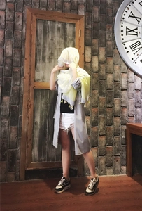 Detail shot of lemon yellow summer scarf with tassels styled against a vintage wall