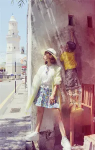 Outdoor shot of a lemon yellow wavy pattern shawl paired with a beach sun hat and lace top