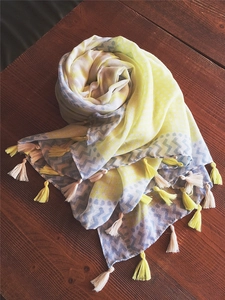 Close-up of yellow and gray wave patterns on a cotton scarf with decorative tassels