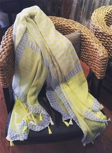 Detail of yellow and grey cotton scarf with wave patterns and fringe on a chair