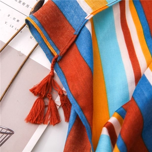 Close-up of vibrant striped cotton linen scarf featuring handmade red tassel details