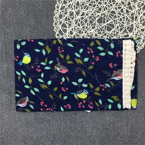 Close-up of bird and berry print on blue fabric with cream lace fringe details