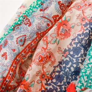 Detailed macro view of bohemian cotton scarf with paisley patterns and red fringe tassels
