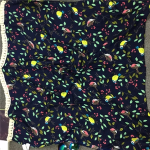 Detailed view of dark blue scarf with vibrant bird prints and white fringe trim
