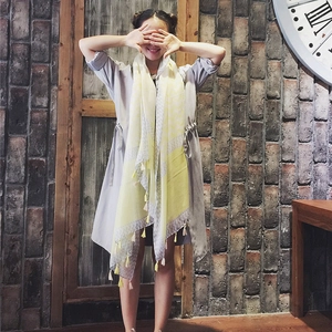 Yellow and grey geometric rhombic scarf with tassels worn over a grey trench coat