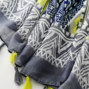Detail of bohemian scarf showing geometric print texture and yellow fringe tassels