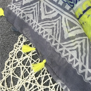 Detail of gray cotton scarf featuring white geometric patterns and neon yellow tassels