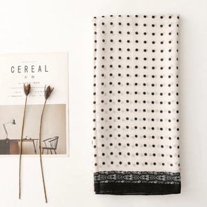 Macro view of long white scarf with black polka dots and intricate mandala border pattern