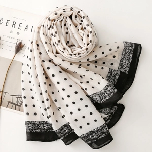 Close-up of black polka dot pattern silk scarf with ornamental border and airy texture