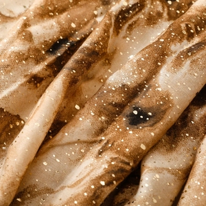 Detailed macro view of marble print scarf with shimmering gold foil accents on soft fabric