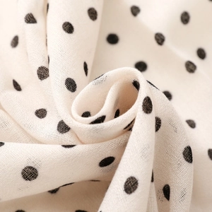 Detail of soft cream fabric with black polka dots and breathable woven texture