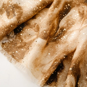 Detail of soft animal print scarf with golden foil texture and fringed edges