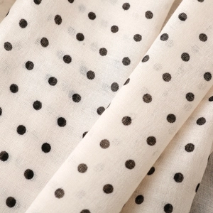 Close-up of vintage black polka dot print on soft cream fabric texture and weave