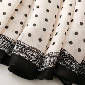 Detail of polka dot scarf with paisley border patterns and soft lightweight fabric texture