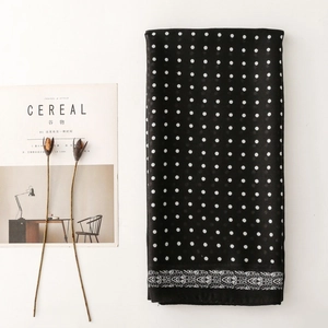 Detail of black polka dot scarf with white ornamental border print and soft texture