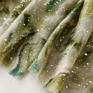 Detail of gray-green marble pattern scarf with gold foil dots and fringe edges