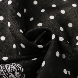 Macro detail of black and white polka dot scarf with intricate paisley border pattern