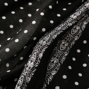 Detailed macro view of black and white polka dot scarf with paisley floral border texture
