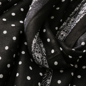 Macro detail of soft fabric with white polka dots and elegant paisley border design