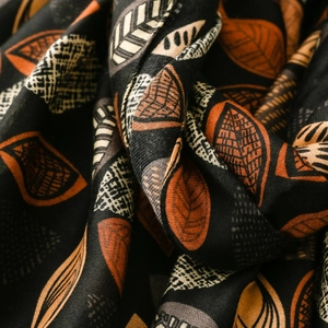 Macro detail of cotton-linen scarf featuring autumn leaf patterns and soft textures