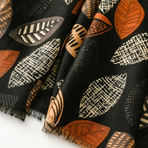 Close-up of cotton-linen feel scarf featuring artistic leaf patterns and fringe edges