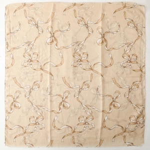 Détail d'un foulard en soie beige avec motifs de nœuds marron et bords ourlés fins