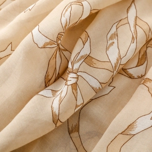 Gros plan d'une écharpe en lin beige avec des motifs de nœuds et texture naturelle