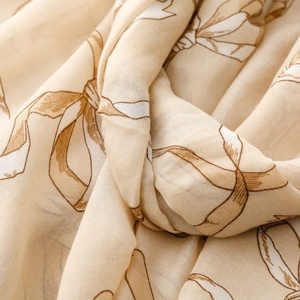 Gros plan sur l'écharpe beige aspect lin avec imprimés nœuds marron et bords effilochés