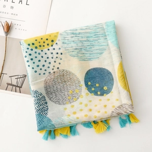 Détail d'une écharpe à motif géométrique de lune avec pompons jaunes et bleus sur blanc