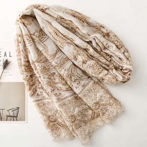 Détail du motif floral doré sur châle beige clair effet coton et lin avec franges