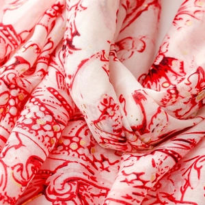 Gros plan du motif cachemire rouge et points dorés sur écharpe blanche en coton